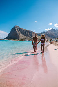 People walking on beach against sky