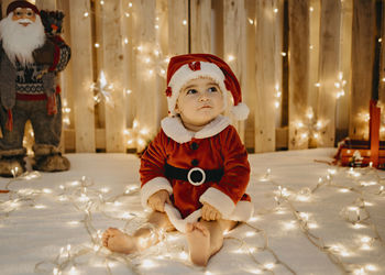 A little girl sitting in a santa claus outfit.