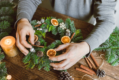 A male florist makes a new year's wreath with fresh fir branches, pine cones and dried fruits.