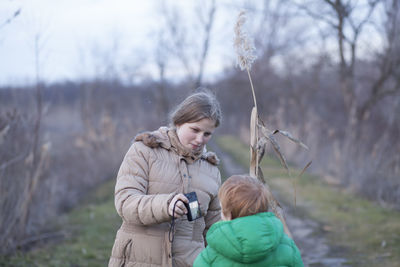 Mother showing camera to son while standing on field during winter