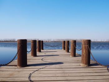 Pier over lake against clear blue sky