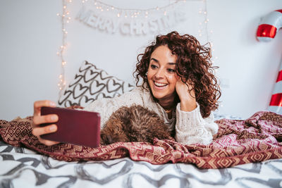 Portrait of smiling young woman lying on bed at home