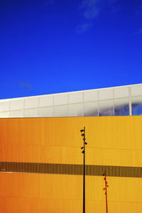 Low angle view of yellow building against blue sky