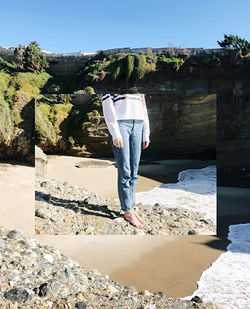 Rear view of man standing on rock against sky