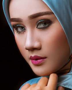 Close-up portrait of a beautiful young woman over black background