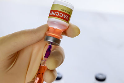 Close-up of hand holding coronavirus vaccine and syringe