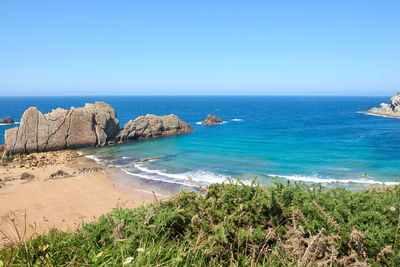 Striking cliffs surrounded by vegetation and a turquoise blue sea.