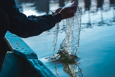 Cropped hand of person collecting water in sea