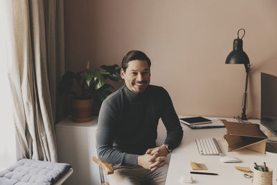 Portrait of smiling male business professional sitting at desk in office