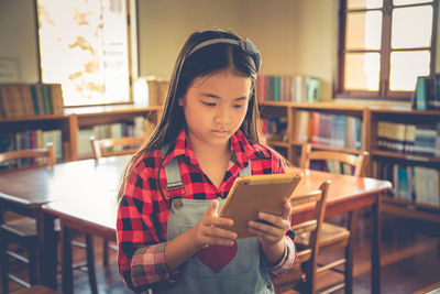 Girl using digital tablet in library