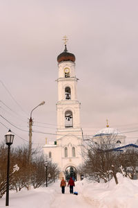 People in front of building against sky during winter