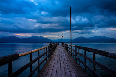 Pier on sea against cloudy sky