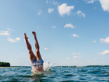 Low section of woman swimming in sea against sky