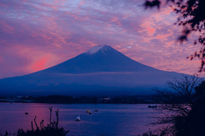 Scenic view of lake by mountains against sky at sunset