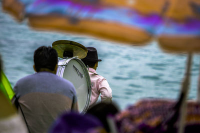 Rear view of musicians carrying drum at beach