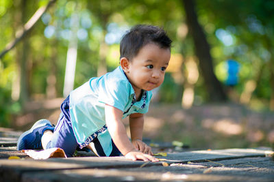 Cute boy looking away while crawling on land