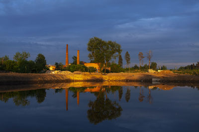 Reflection of factory on lake against sky