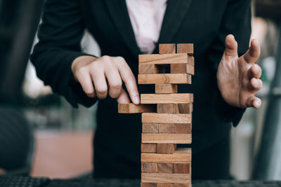 Midsection of businesswoman stacking toy blocks on table