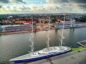 Sailboats moored on river in city against sky