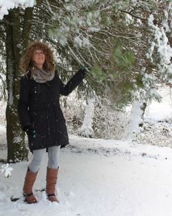 Full length of woman standing on snow covered tree