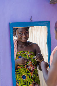 Portrait of a smiling young woman holding blue while standing outdoors