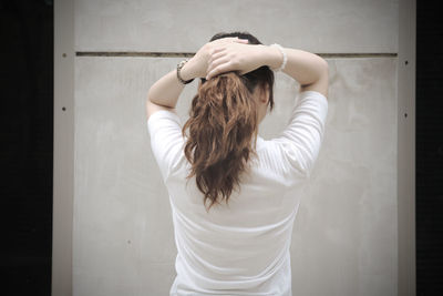 Rear view of woman standing against white wall