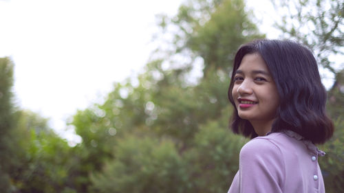 Portrait of smiling girl against trees