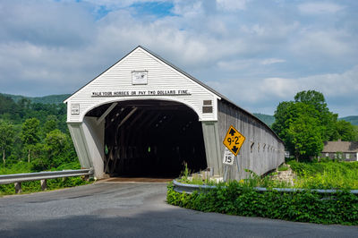 Information sign on road by building against sky