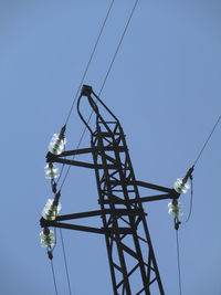 Low angle view of electricity pylon against clear sky