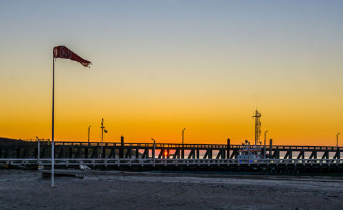 Silhouette poles on beach against sky during sunset