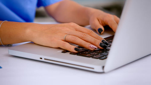 Cropped hands of businesswoman using laptop at home