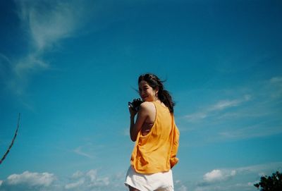 Low angle view of woman standing against sky