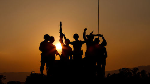Silhouette group of special forces sodiers hold the guns on tank to indicative of their victory 