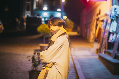 Side view of woman standing on street in city