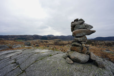 Stack of stones on rock against sky