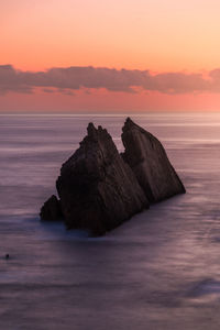 Rocks on sea against sky during sunset