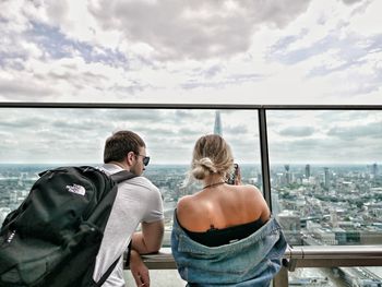 Rear view of people looking at cityscape against sky