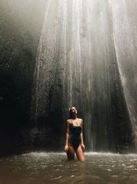 Woman standing under waterfall