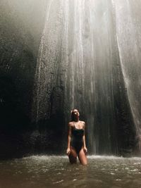 Full length of shirtless man standing in forest