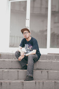 Full length of young man sitting on wall