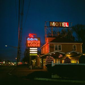 Information sign by illuminated building against sky at night