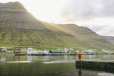 Man standing on pier against town and mountains