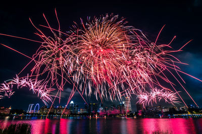 Low angle view of firework display over river at night