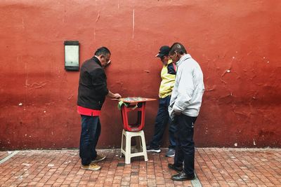 Full length of friends standing against wall