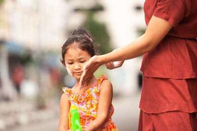 Midsection of mother applying face paint on daughter face