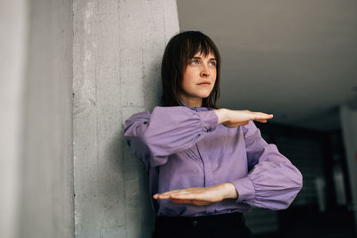 Portrait of a young woman standing against wall