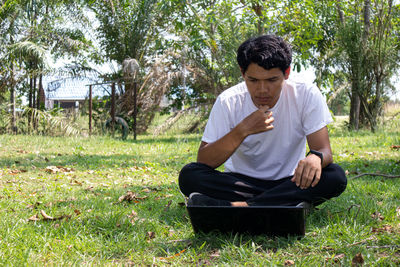 Young man sitting on field