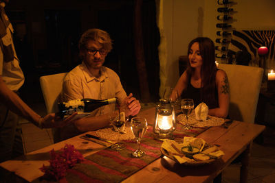 Friends sitting on table at illuminated cafe