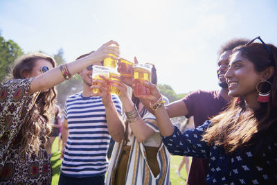 Friends toasting drinks in glasses against sky