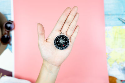 Close-up of hand holding clock against blurred background